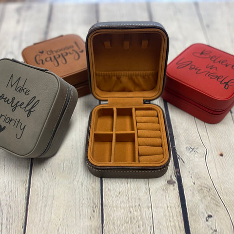 4 leatherette jewelry boxes shown left to right in grey, rawhide, an open box to show the inside and red