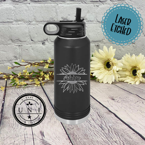 Black water bottle tumbler with background of white brick and wood  with yellow flowers