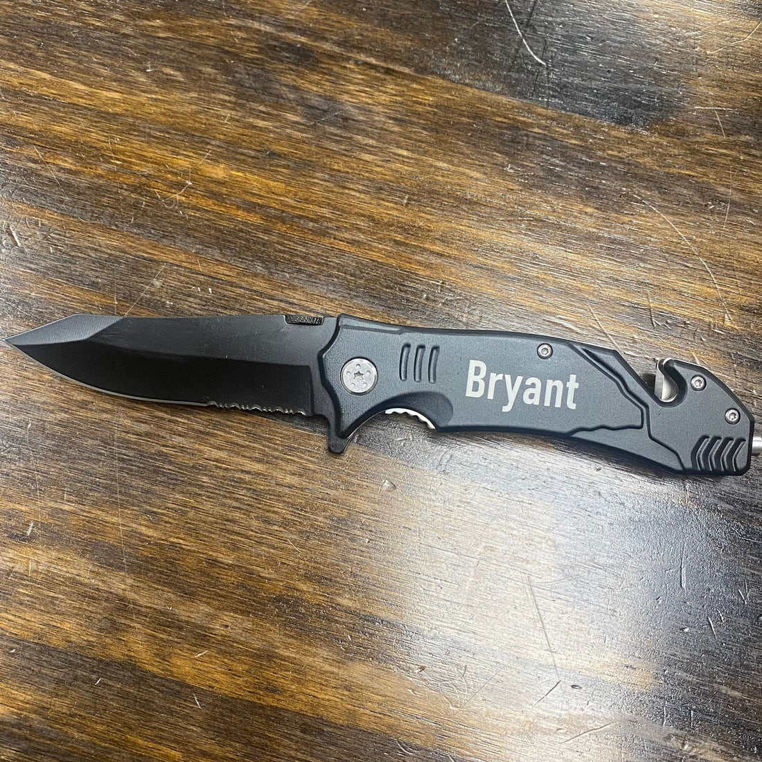 Folding knife with 'Bryant' branding on a wooden surface
