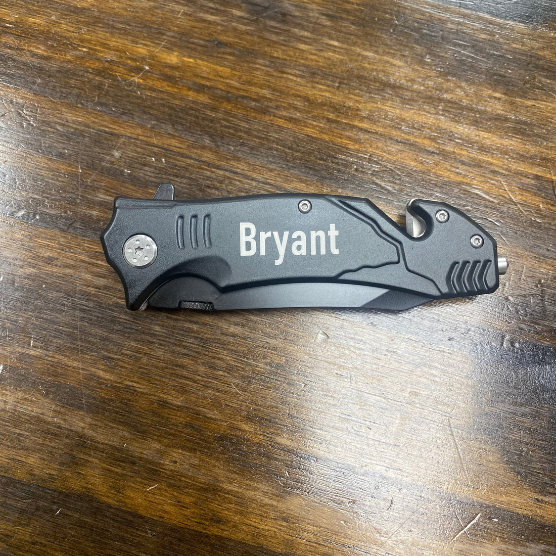 Folding knife with 'Bryant' engraving on a wooden surface