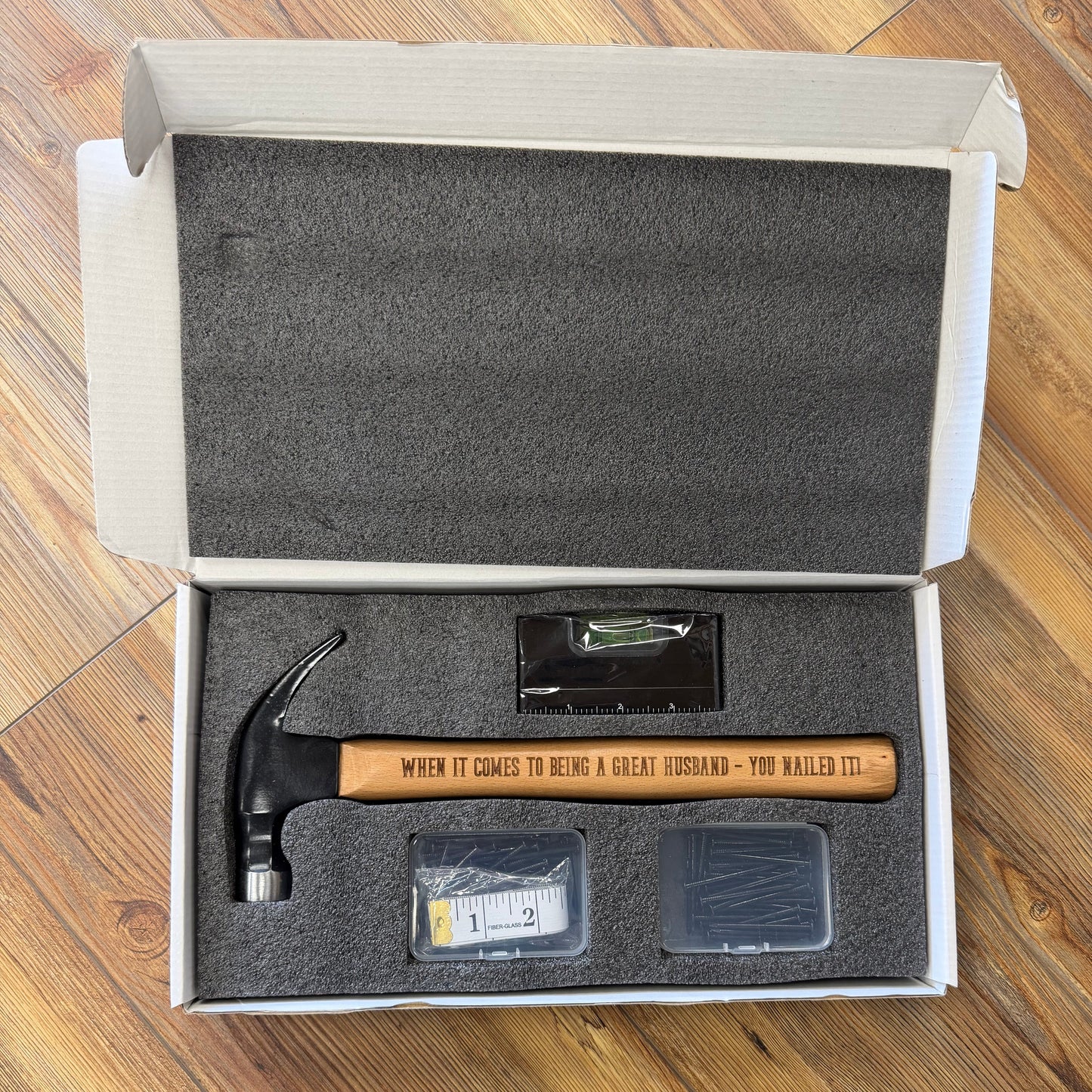 Hammer with a wooden handle in an open box on a wooden surface