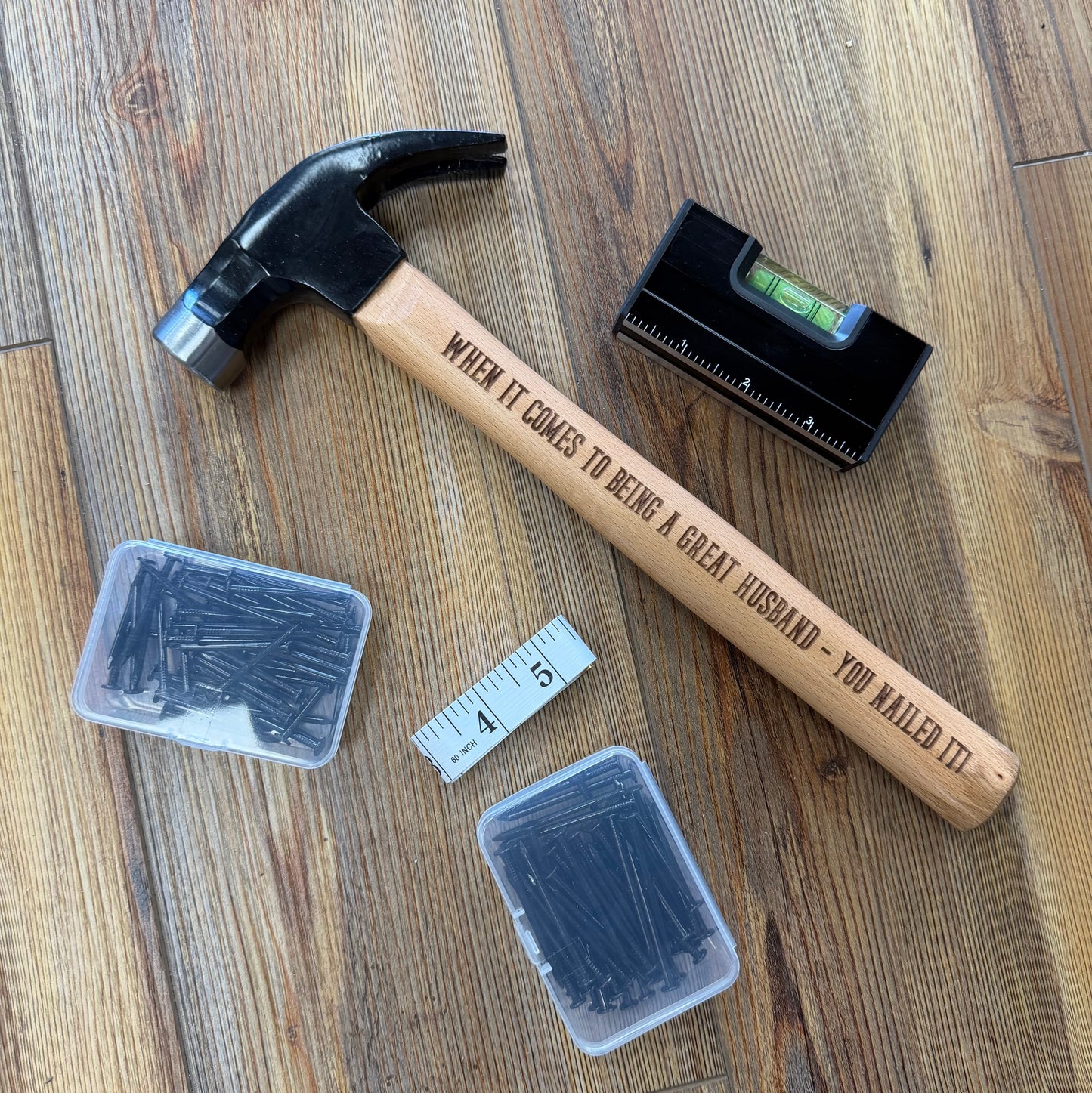 Hammer, level, and containers of nails on a wooden surface