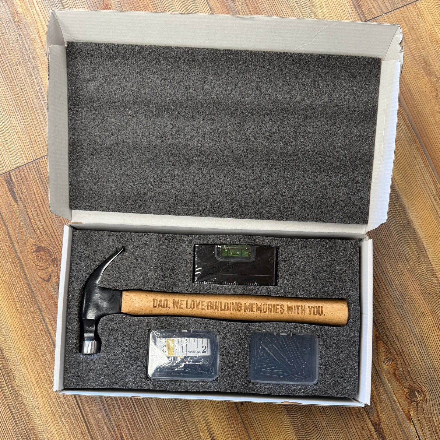 Hammer and digital scale in a box on a wooden surface