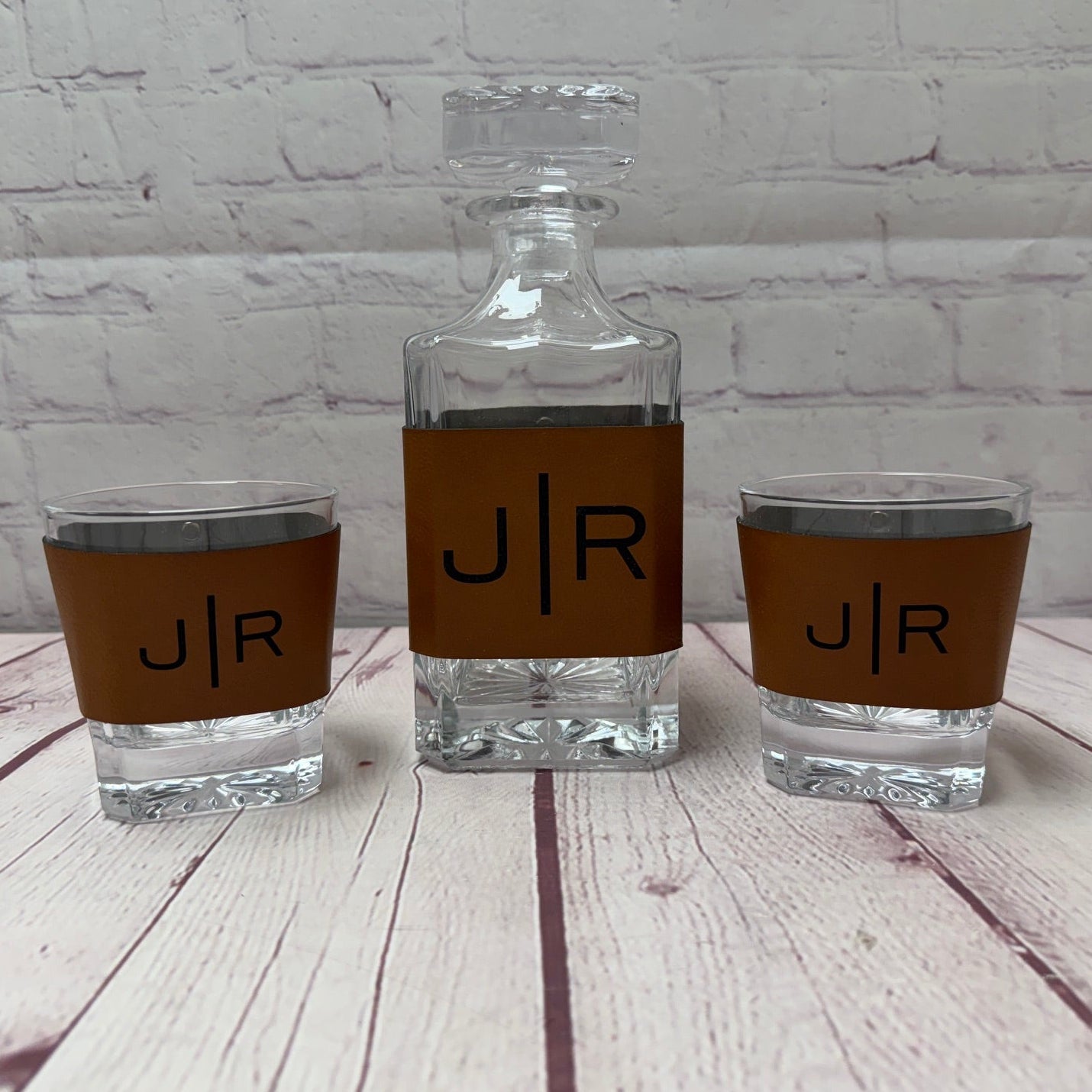 Three glass drinkware items with 'J/R' branding on a wooden surface.