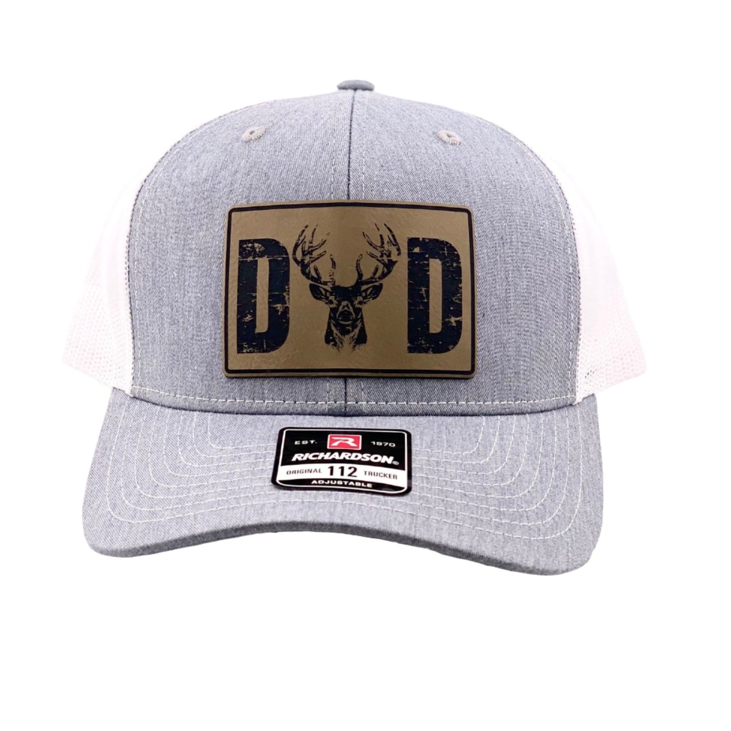 A trucker hat with a leather patch on the front featuring a gold 'DAD' deer logo against a grey background.