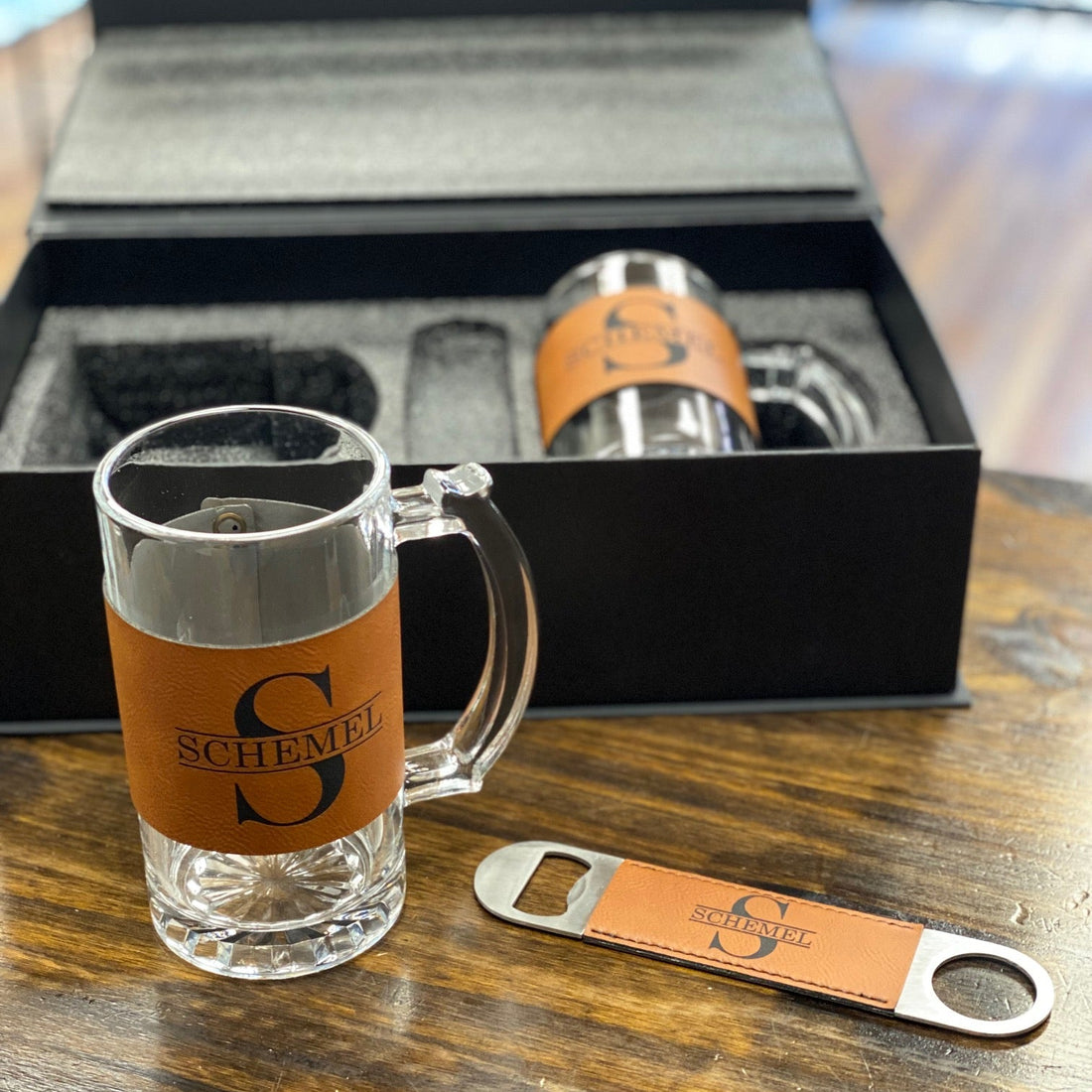 Glass mug, bottle opener, and branded box on a wooden surface