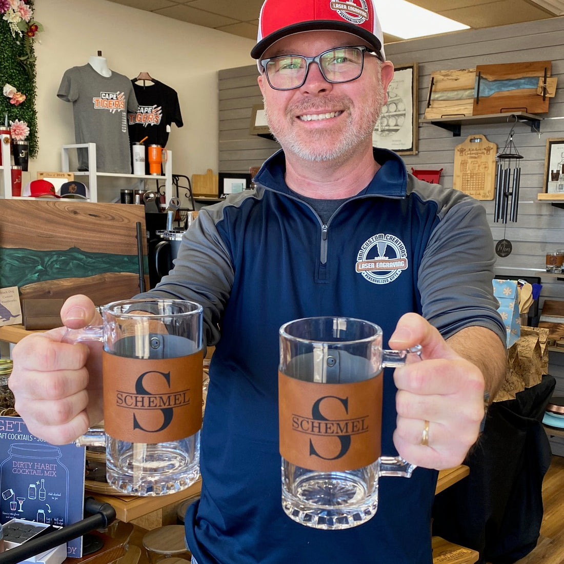 Man holding two glass mugs with a brand logo in a casual setting