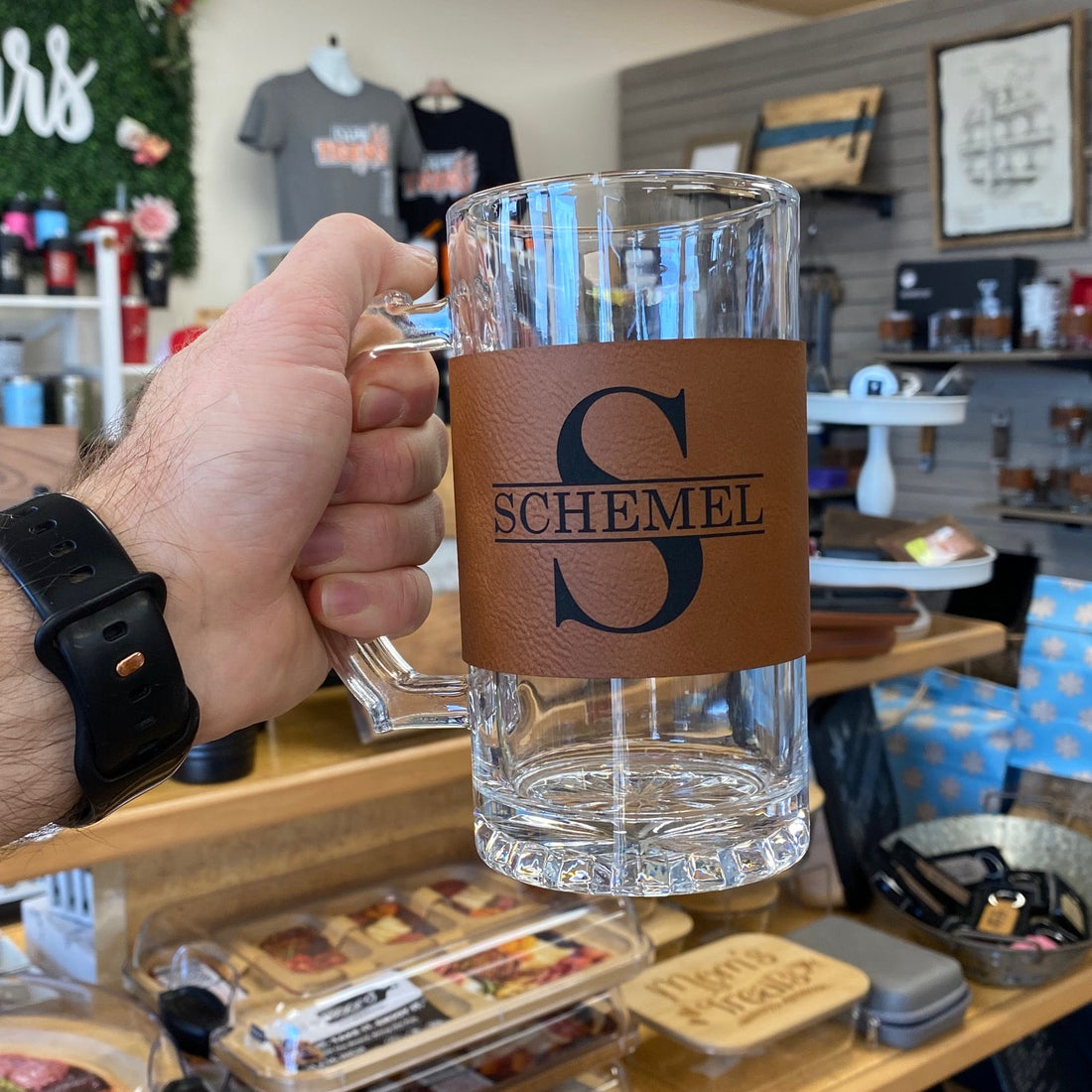 Hand holding a glass with a brand logo in a store setting