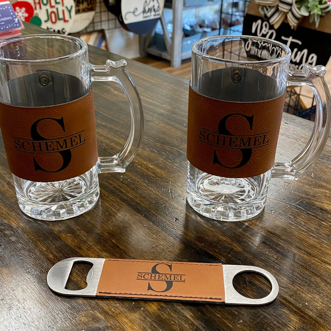 Two glass mugs with brown labels and a bottle opener on a wooden surface.