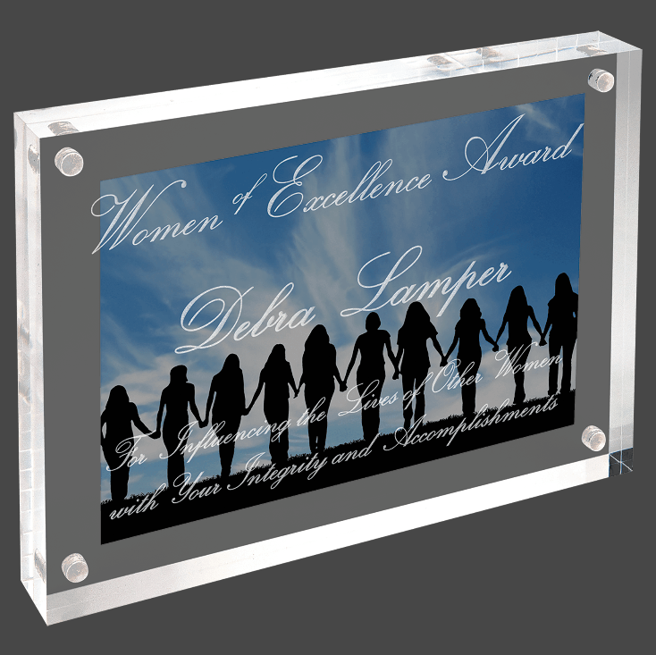 A clear acrylic award with a magnetic back, featuring personalized engraving text that reads 'Woman & Excellence Award' with additional text that reads 'Delbra Lampier' and 'With Your Integrity & Dedication', along with a graphic of silhouetted female figures joining hands.